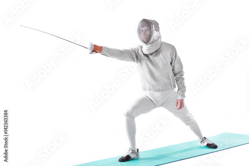 side view of fencer in uniform training with rapier in hand on white