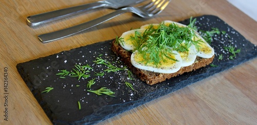 Traditional danish open sandwich with egg, sour cream, dill, salt and pepper photo