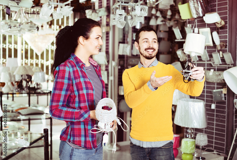 Smiling man and girl in lighter shop discussing purchase of night light