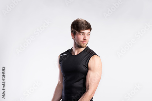 Handsome fitness man in black sleeveless shirt, studio shot. © Halfpoint
