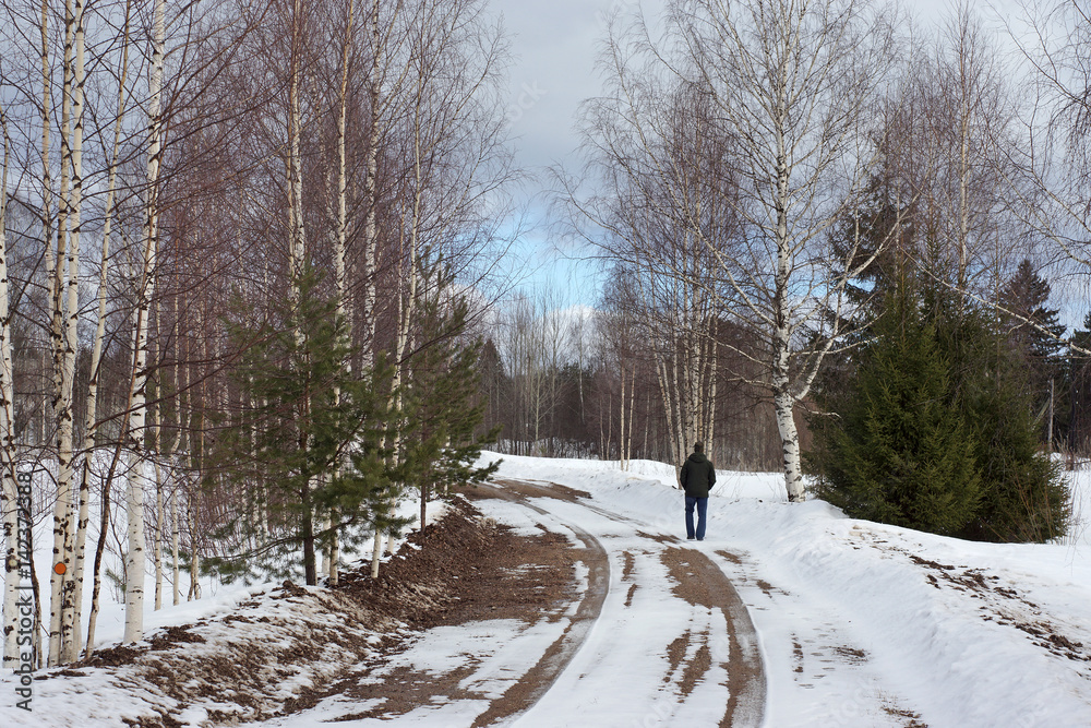 Man walking on a rural road in early spring