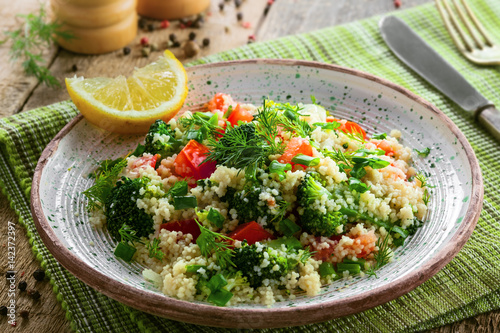 Delicious healthy meal made of couscous, broccoli and other vegetables on a rustic wooden table. Traditional eastern food. Close-up shot.