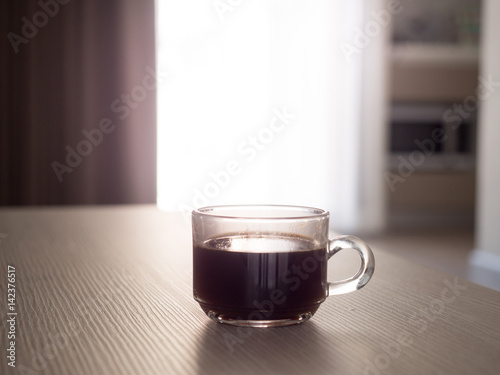 A cup of coffee and notebook on wood table . Coffee break in morning ,break working / selective focus.Blank seating indoor in living room .copy space for create idea for business.