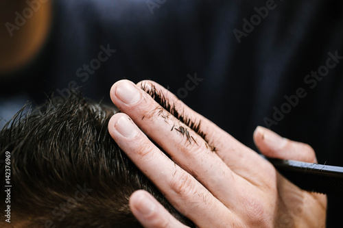 Man's wet hair on barber's long fingers