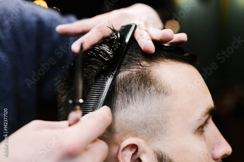 Barber brushes man's wet hair while he cuts it