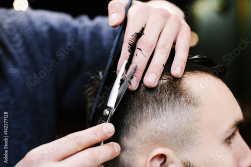 Barber brushes man's wet hair while he cuts it