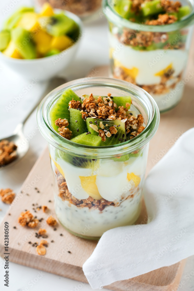 Yogurt granola parfait with mango,kiwi, tropical fruits аnd сhia seeds, layered dessert or breakfast. Selective focus. Yogurt granola parfait with mango,kiwi, tropical fruits аnd сhia seeds, layered dessert or breakfast. Selective focus.