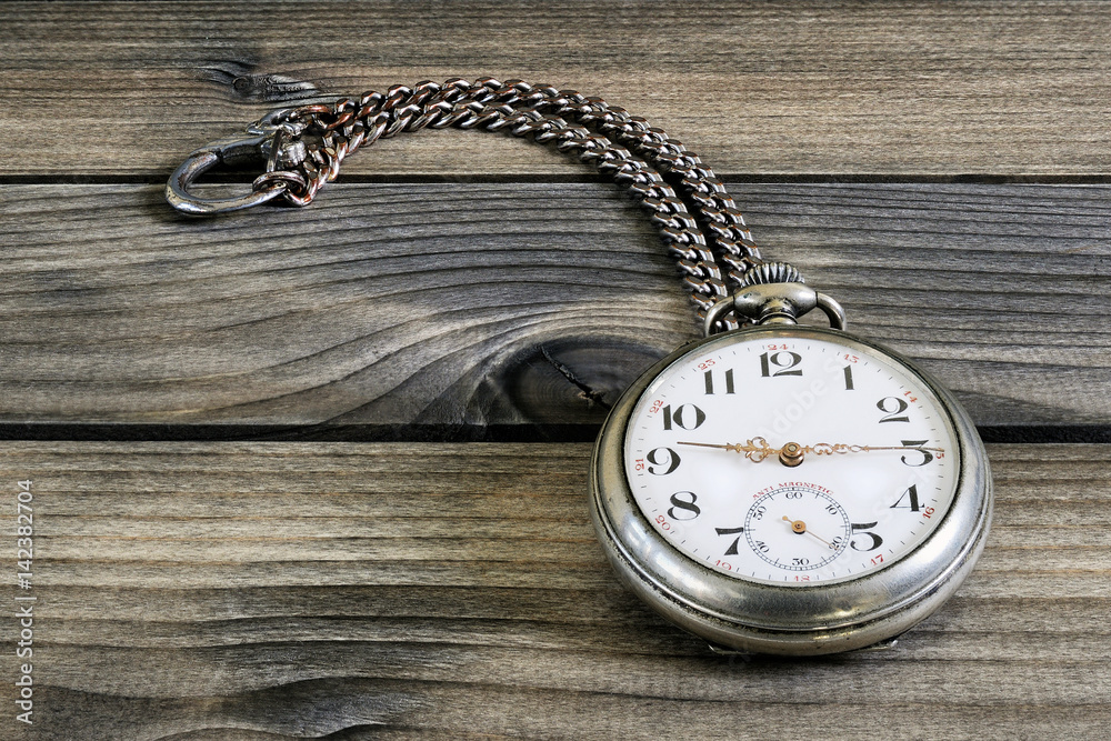 Close up of an antique pocket watch on an antique wooden table