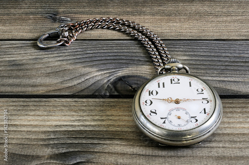 Close up of an antique pocket watch on an antique wooden table