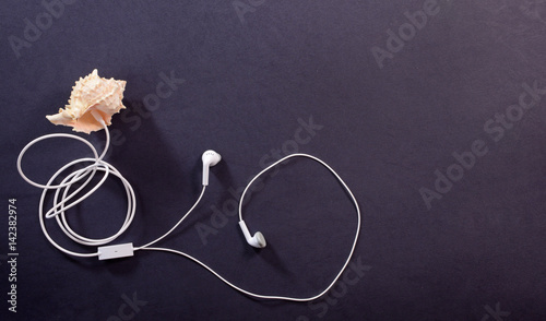 White headphones and seashell on a dark background closeup