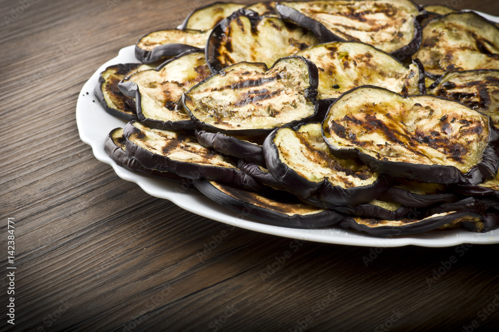 Aubergines eggplants and slices grilled on the plate Aubergines eggplants and slices grilled on the plate