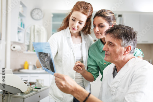 Two female dentists attend to a male patient, providing expert dental care with precision and care.