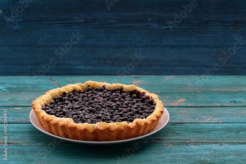 Homemade open pie with wild blueberries on blue wooden table