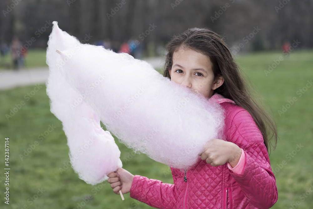 Girl with loose hair eating candy floss in the park Girl with loose hair eating candy floss in the park