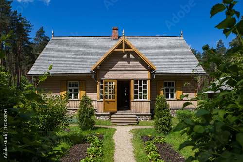 Wooden rural house and green garden, Baltic traditions, Latvia