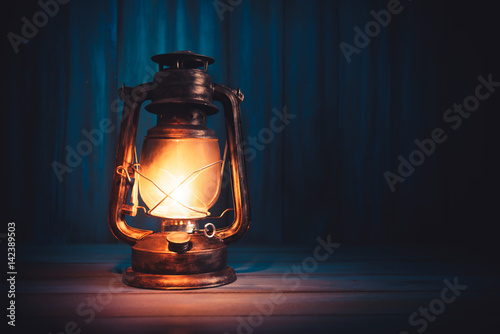 Fotografia kerosene lamp on a wooden background with dramatic lighting