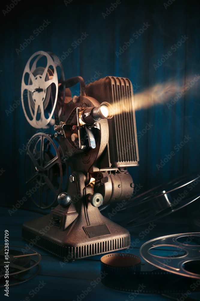 vintage 8mm movie projector with 35mm reels and film on a wooden