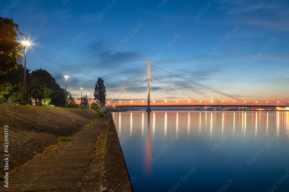 Deep sunset panoramic scene over Daugava river in Riga, Latvia. New business buildings and cable-stayed bridge