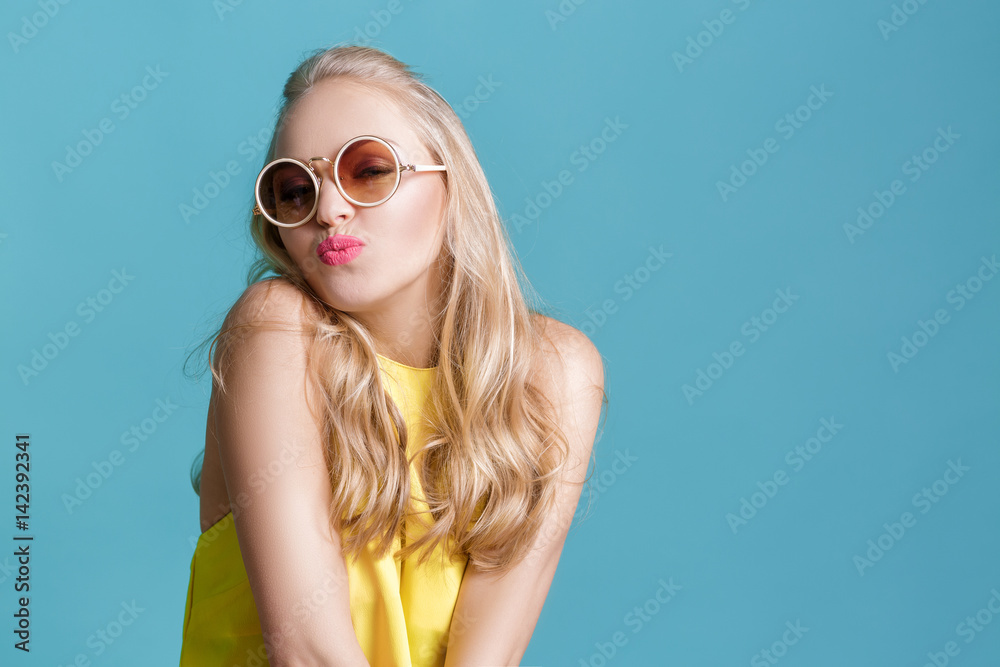 portrait of beautiful blond woman in sunglasses and yellow shirt on blue background. Carefree summer. portrait of beautiful blond woman in sunglasses and yellow shirt on blue background. Carefree summer.