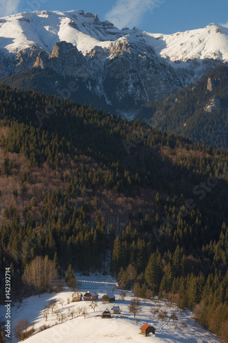 Beautiful winter mountain landscape with snowflakes in frosty winter day. Carpathian wild mountains. Romania. Holbav. Bran. Brasov. Romania. Little noise. Colorful winter sky.