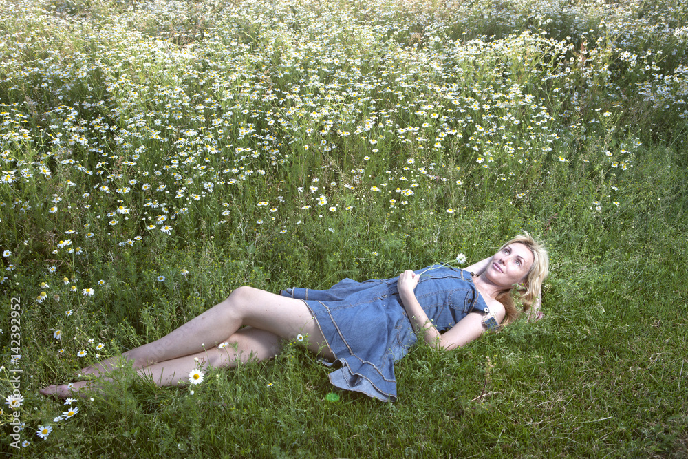 The beautiful happy young woman lies in the field of chamomiles The beautiful happy young woman lies in the field of chamomiles