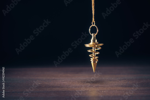 Pendulum used for readings and hypnotism on a wooden background