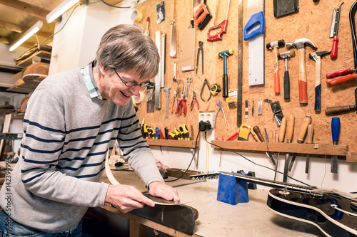 Smiling musical instrument maker working on a guitar