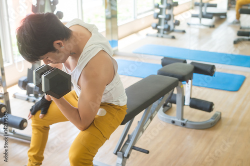 young handsome asian man works out exercise weights lifting in modern gym