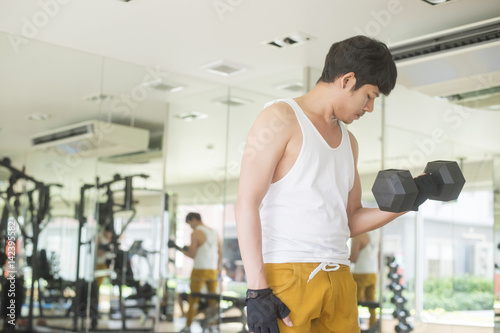 young handsome asian man works out exercise weights lifting in modern gym