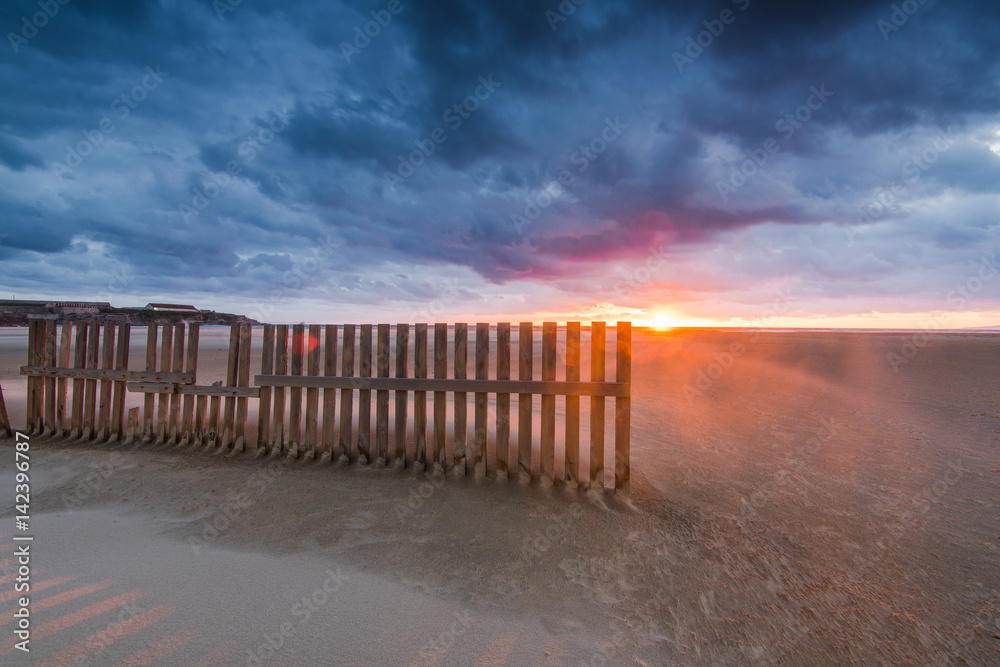 wooden fences on beach in Tarifa, sunset after dramatic storm