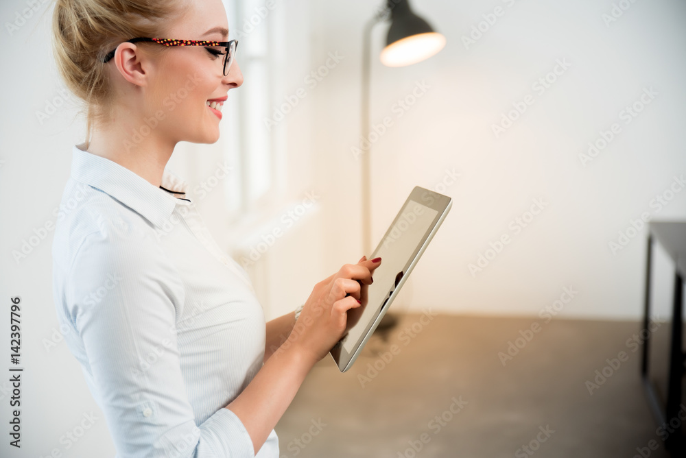 Casual businesswoman using tablet PC in a bright office Casual businesswoman using tablet PC in a bright office