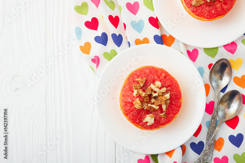 Baked grapefruit with walnuts on a white background. Top view with space for text.