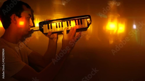 Young man playing the melodica in spotlight photo