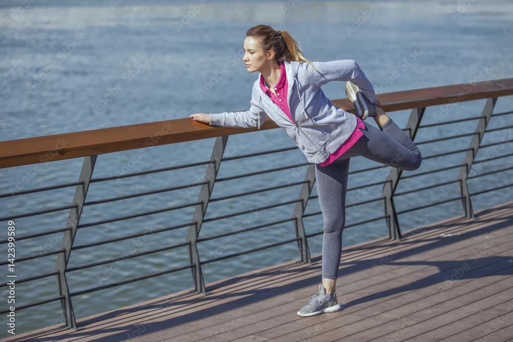 Morning exercise along the river. A young woman on recreation and jogging Morning exercise along the river. A young woman on recreation and jogging