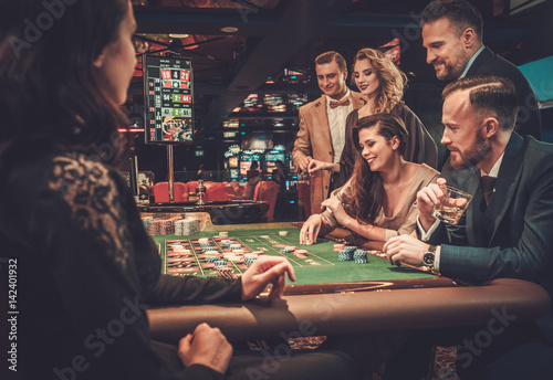 Upper class friends gambling in a casino photo