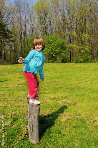 Fotografie Little girl standing on the two big logs in the park