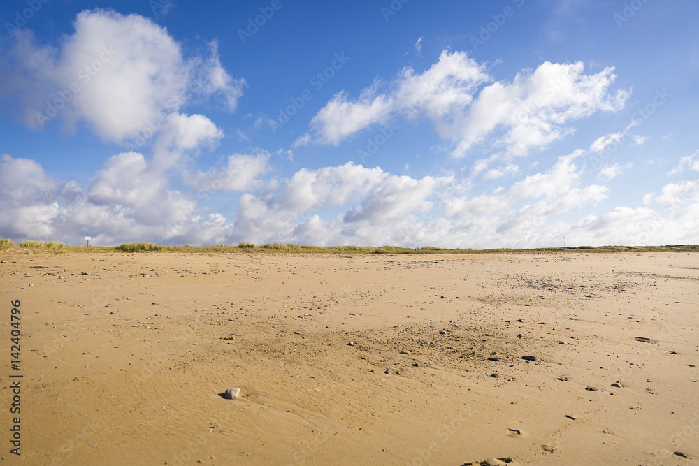 sandy beach in Vendee, France with blue sky and white clouds