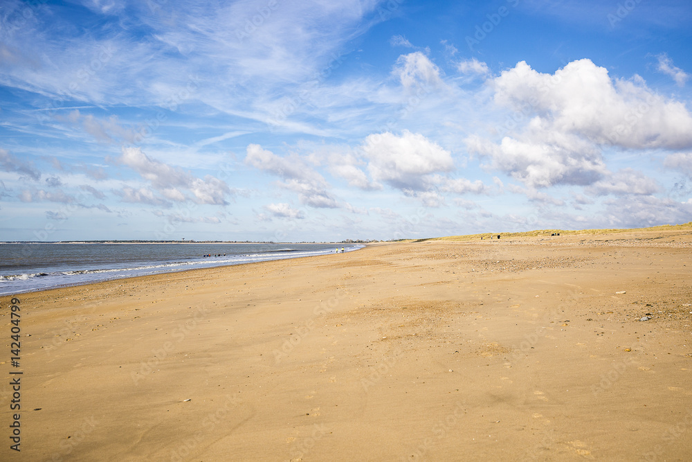 sandy beach in Vendee, France with blue sky and white clouds