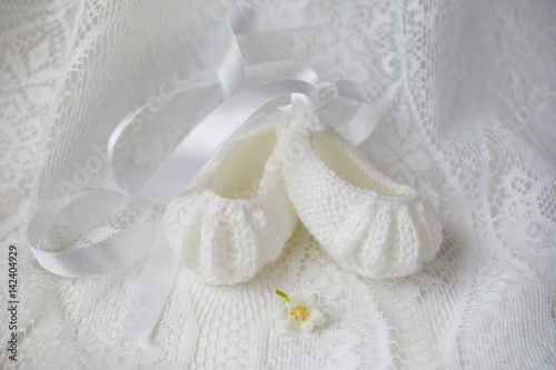 Knitted baby ballet shoes on lace background