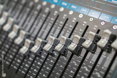 Side closeup on a sliders of a mixing console. It is used for audio signals modifications to achieve the desired output. Applied in recording studios, broadcasting, television and film post-production