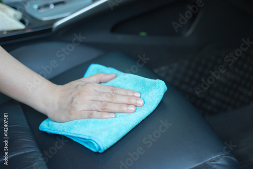 Hand with microfiber cloth cleaning car.cleaning leather car seat with microfiber cloth,auto detailing and valeting concept,cleaning car interior,car wash carcare station,selective focus,vintage color