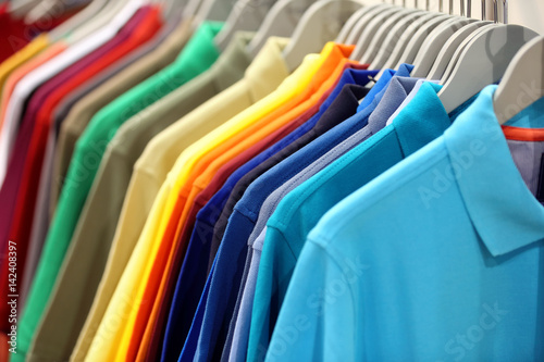 Row of men's polo shirts in wardrobe or store