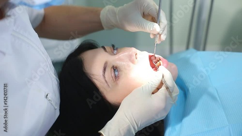 The dentist begins to examine the oral cavity of a beautiful girl