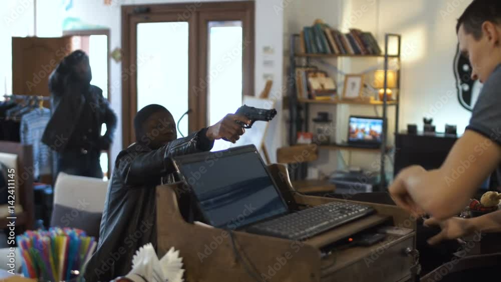 Two African and Caucasian people walking into the shop and aiming to the assistant with guns. 4K gimbal stabilized shot