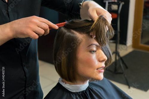 Male hairdresser is preparing for haircut of Beautiful woman in the beauty salon.