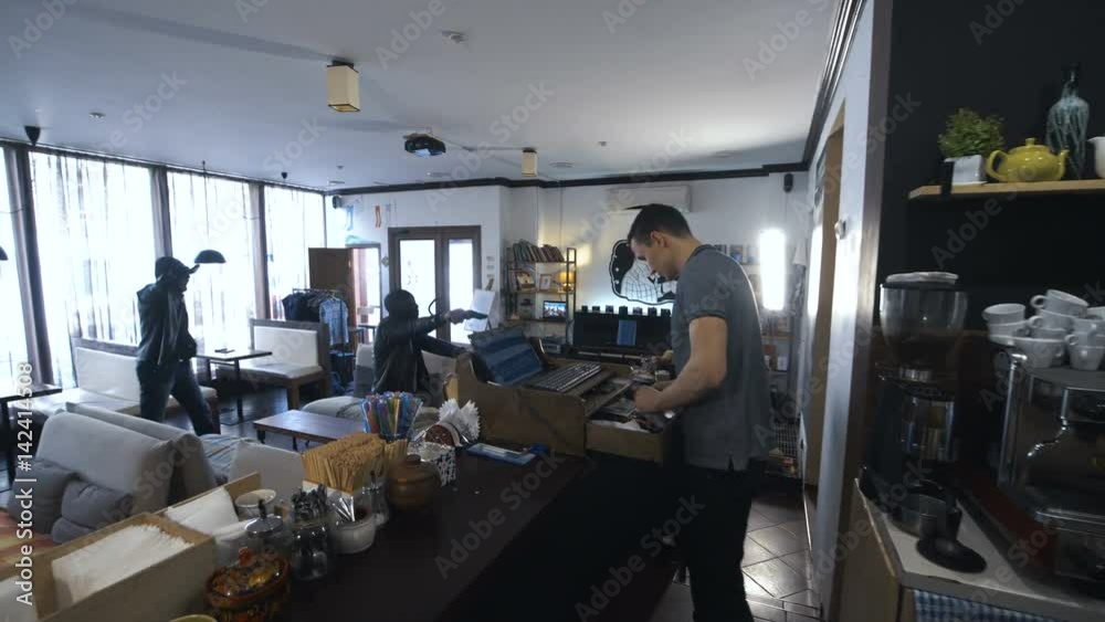 Two African people walking into the shop and aiming to the assistant with guns. Two African people walking into the shop and aiming to the assistant with guns.