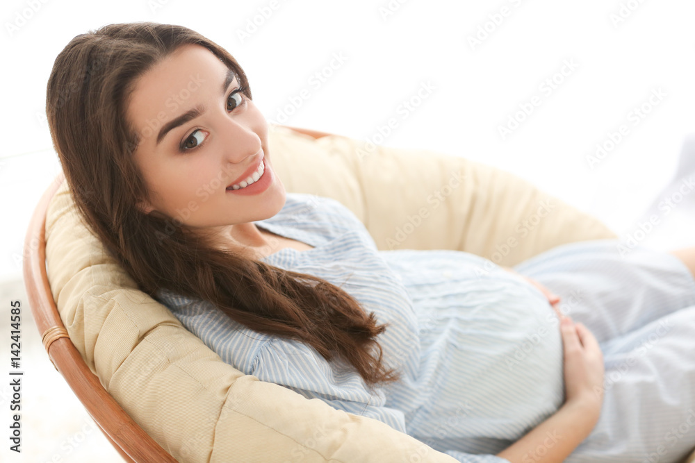 Beautiful pregnant woman sitting on lounge at home Beautiful pregnant woman sitting on lounge at home