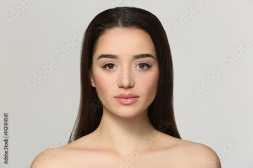 Beautiful young woman on light background