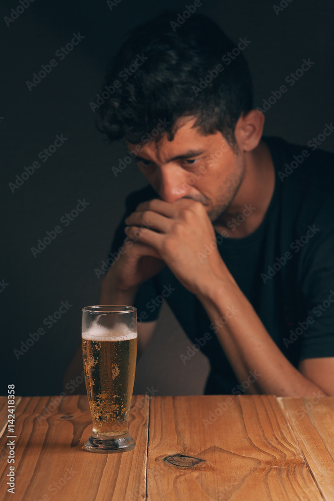 Concept of alcoholism. Sad man at the table with a glass of beer in a dark  room. Stock Photo | Adobe Stock