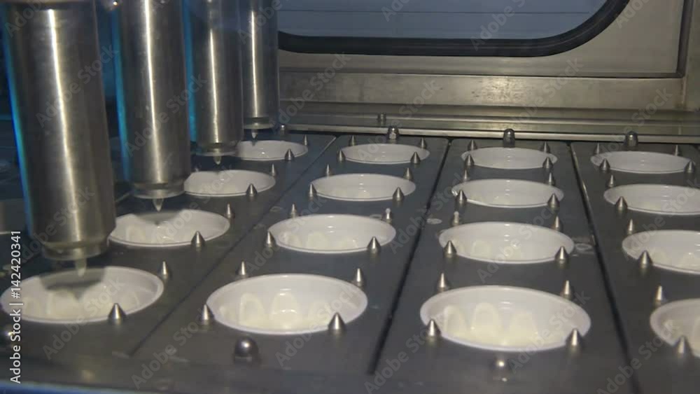Manufacture of sour cream. Of industrial machine pouring sour cream into empty cans at modern production plant, working conveyor. Manufacture of sour cream. Of industrial machine pouring sour cream into empty cans at modern production plant, working conveyor.